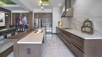 A large kitchen with marble counter tops and a dining room with a table and chairs